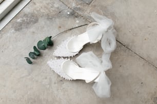 a pair of white shoes with a flower on the ground