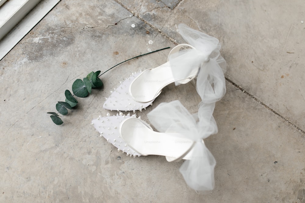 a pair of white shoes with a flower on the ground