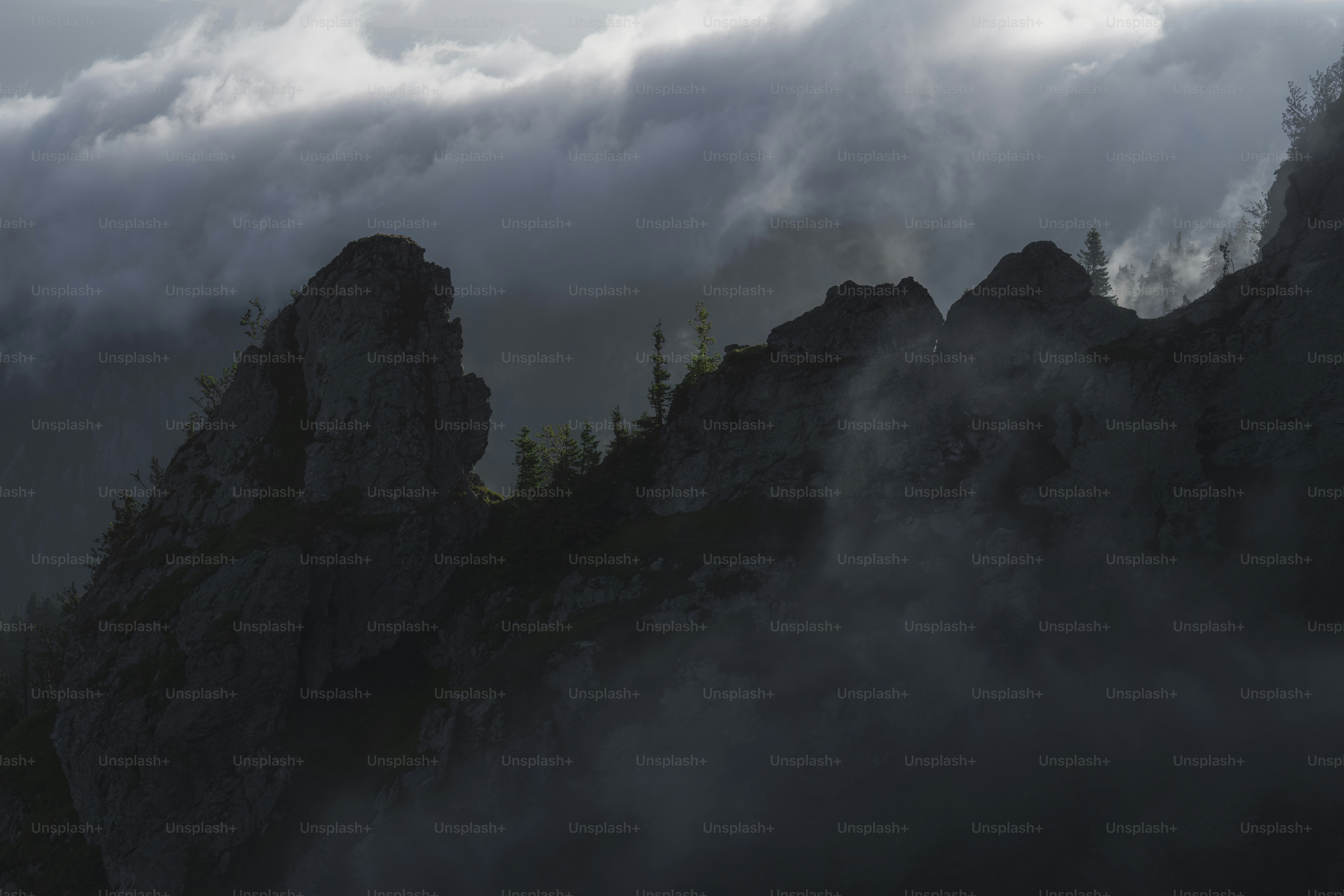 A mountain covered in fog and clouds under a cloudy sky photo – Moody ...