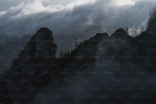 a mountain covered in fog and clouds under a cloudy sky