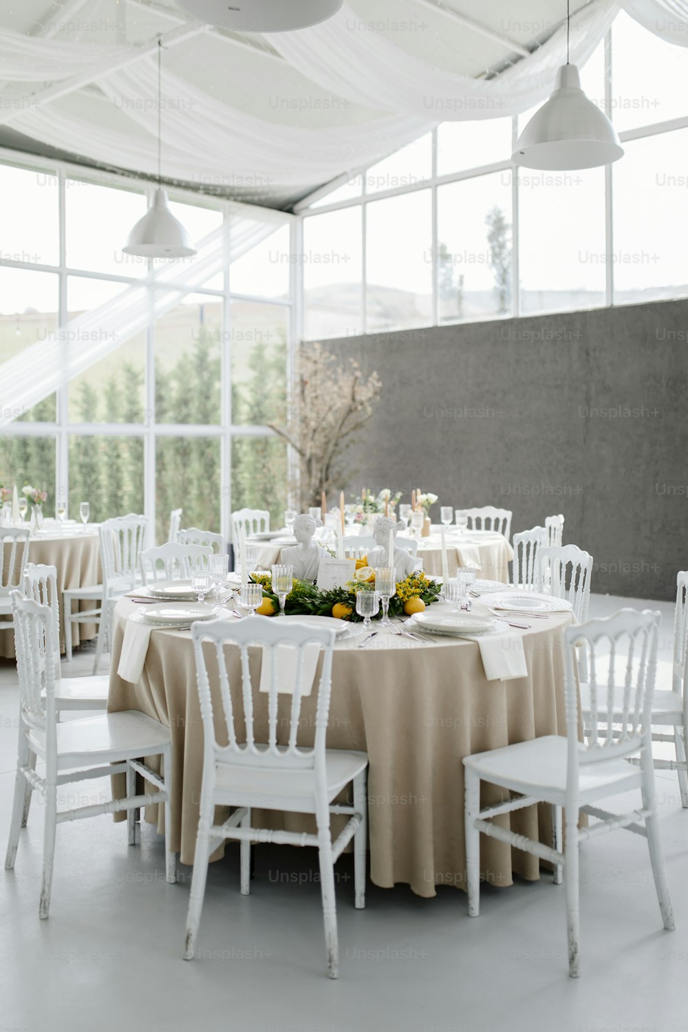 un tavolo apparecchiato con sedie bianche e fiori gialli
