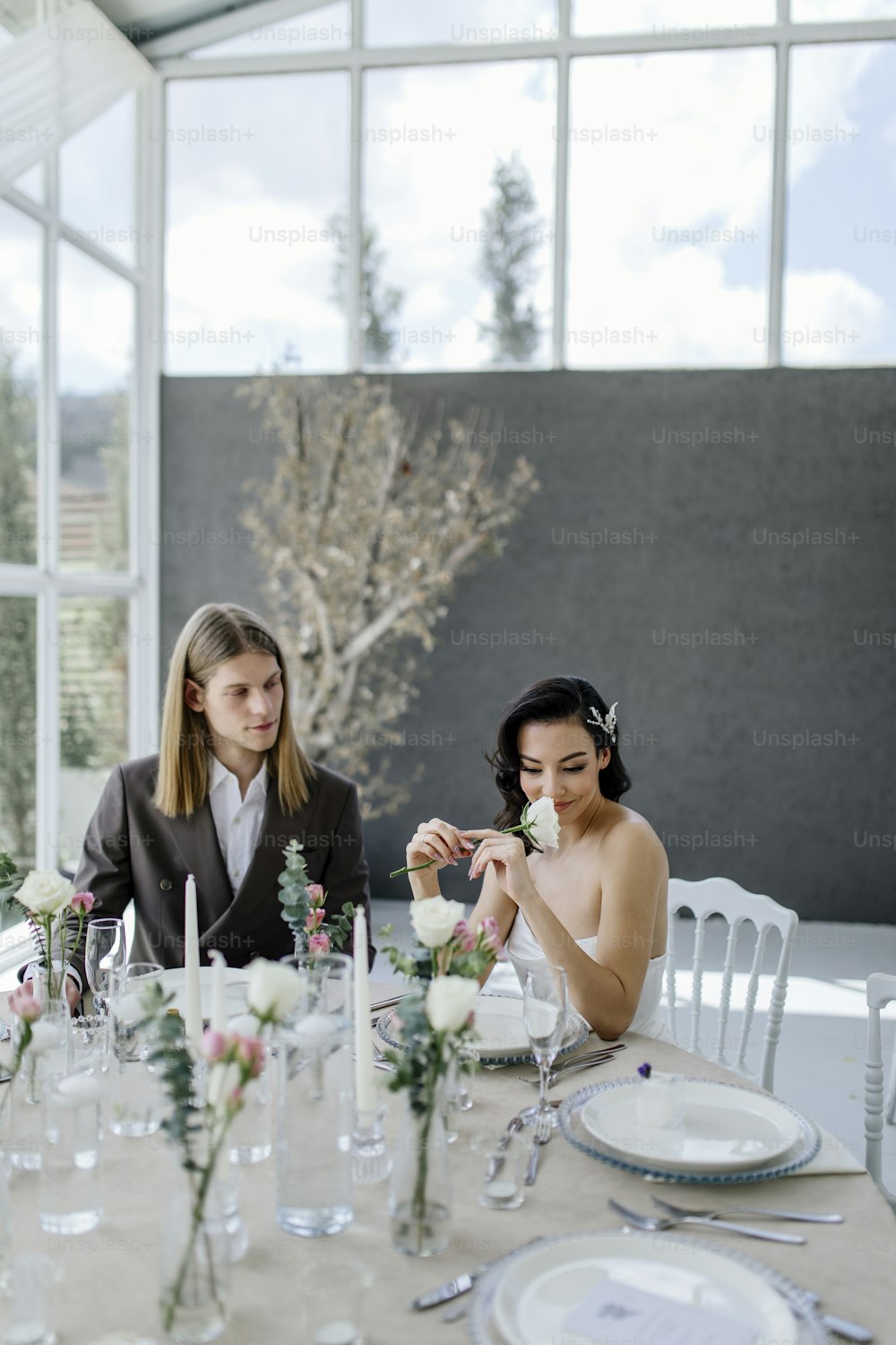 deux femmes assises à une table avec des fleurs dans des vases