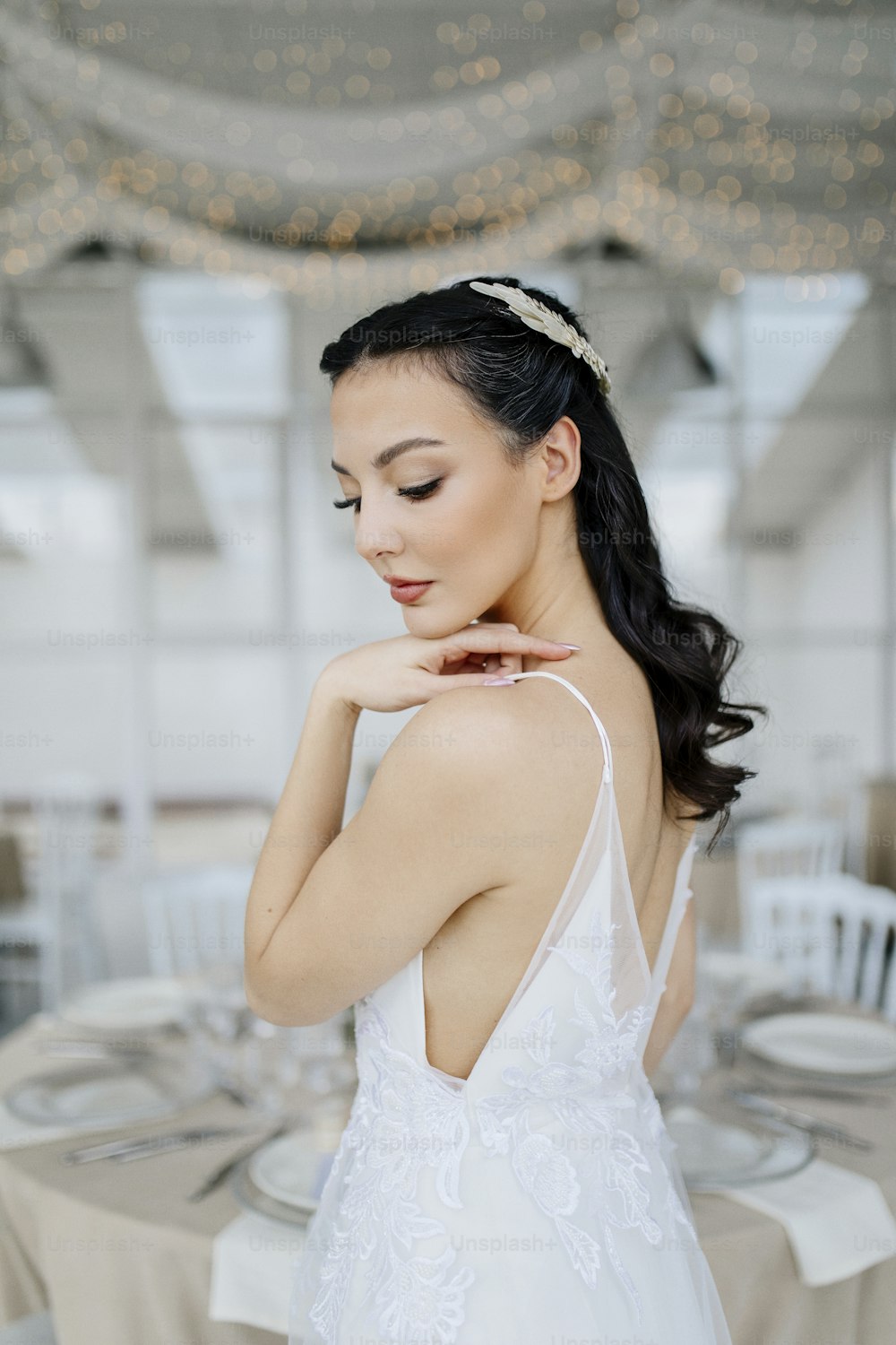 a woman in a white dress is standing near a table