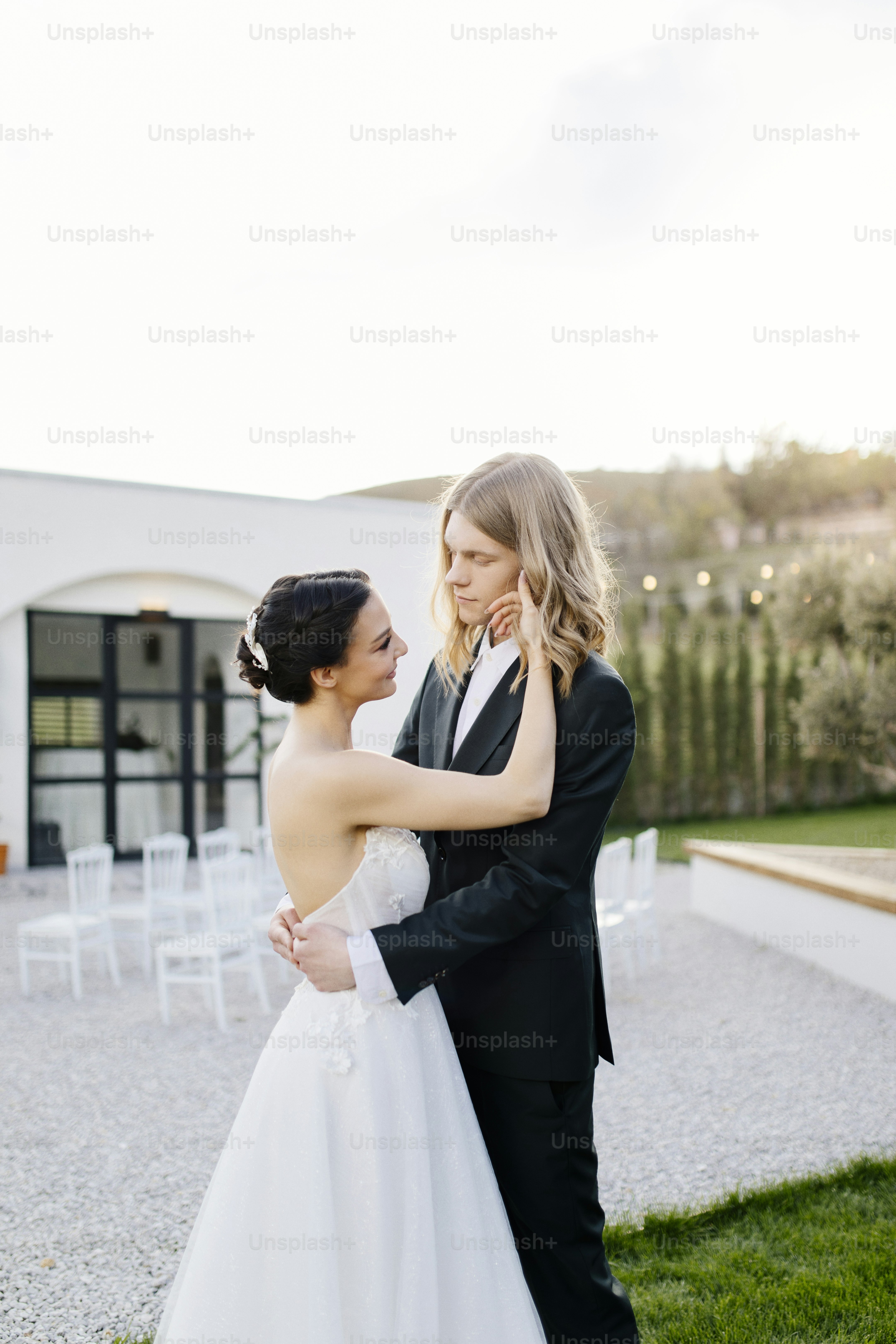 A bride and groom standing in front of a white building photo – Wedding ...