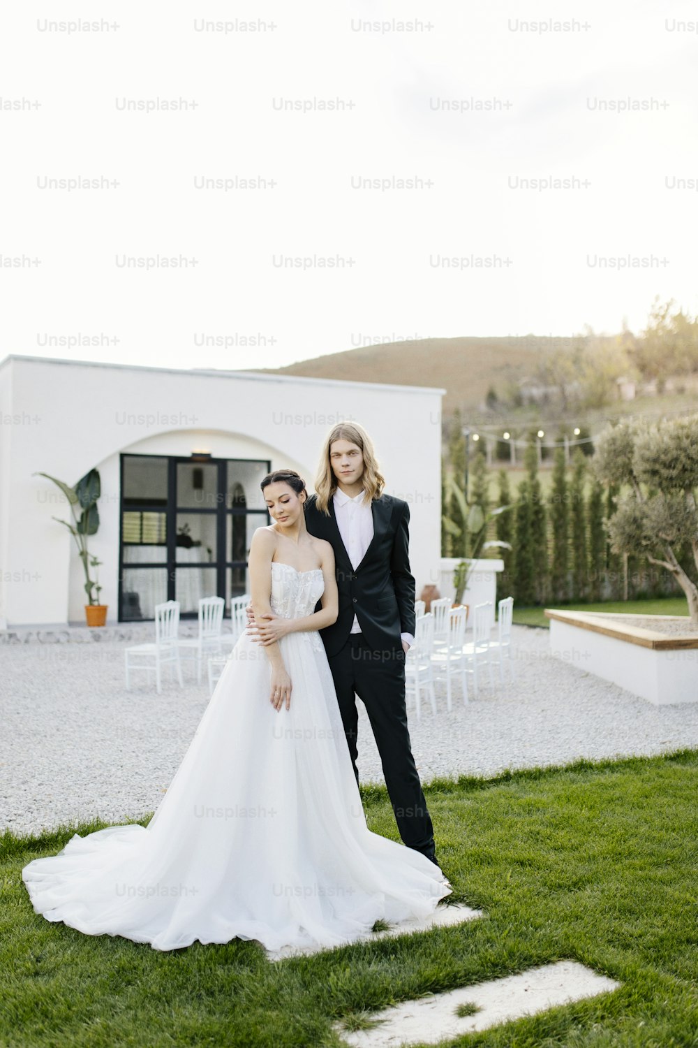a bride and groom posing for a photo in front of a house