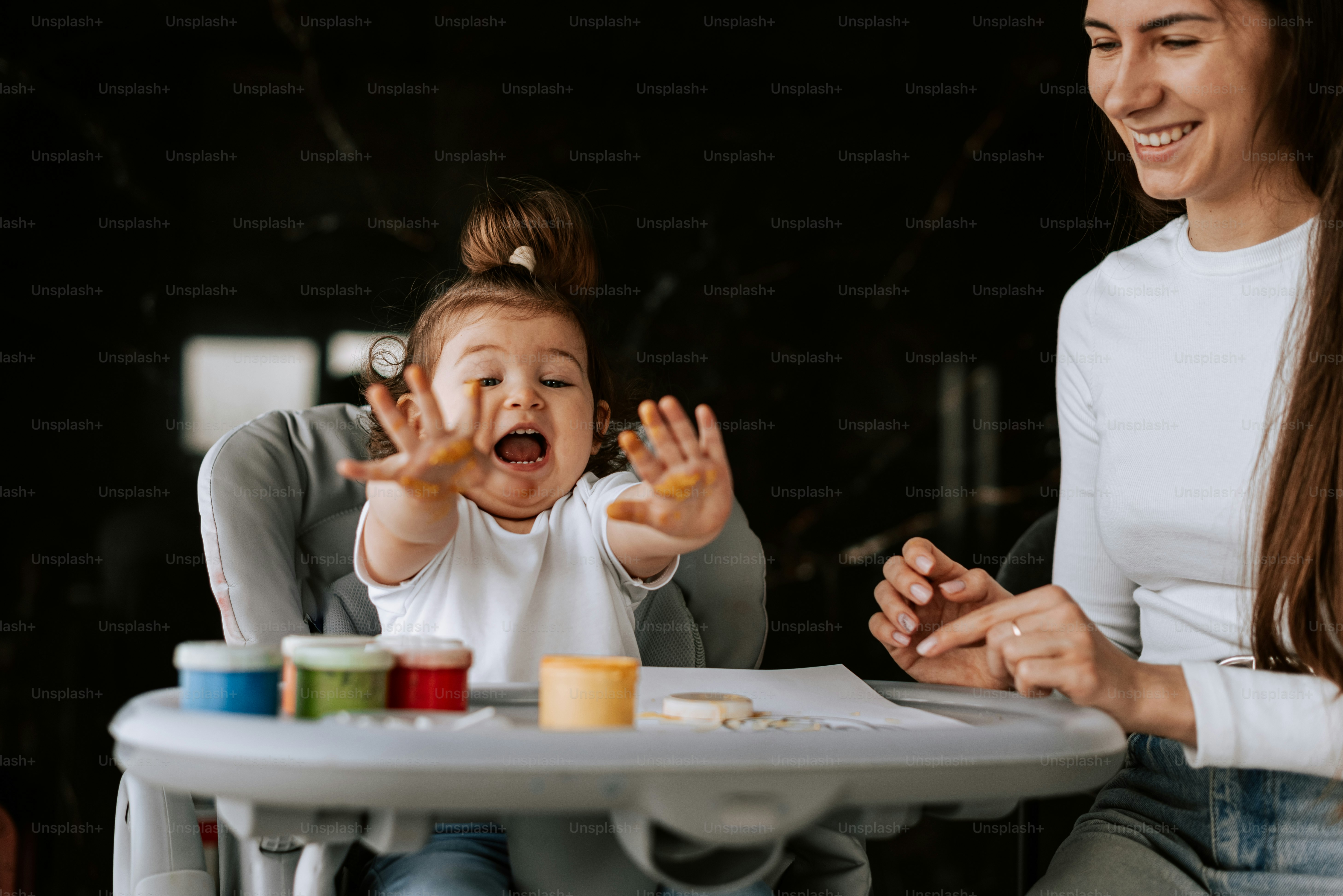 a woman sitting at a table with a baby in a high chair