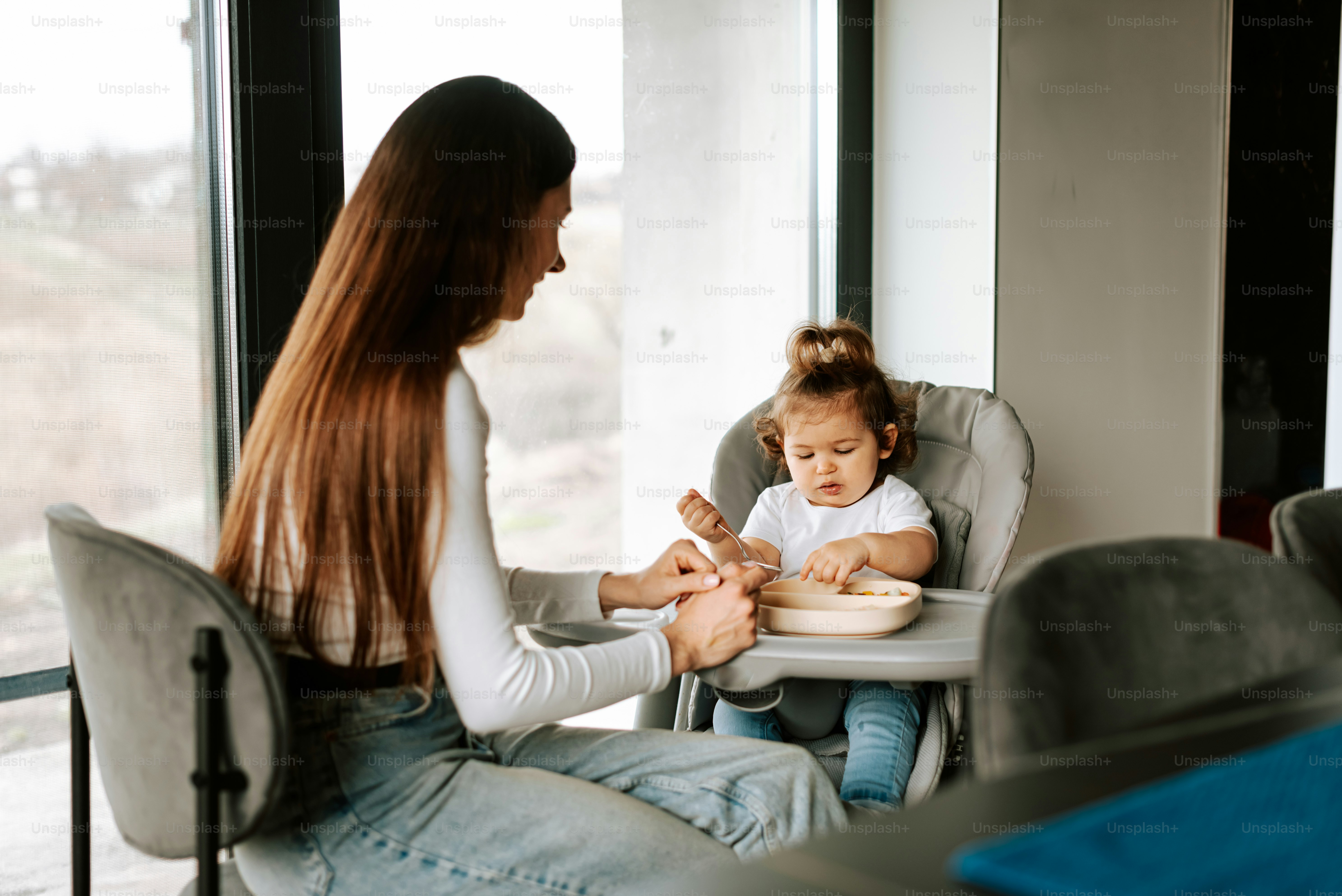 a woman sitting in a high chair feeding a baby