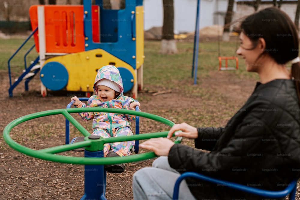 a woman sitting next to a child on a playground