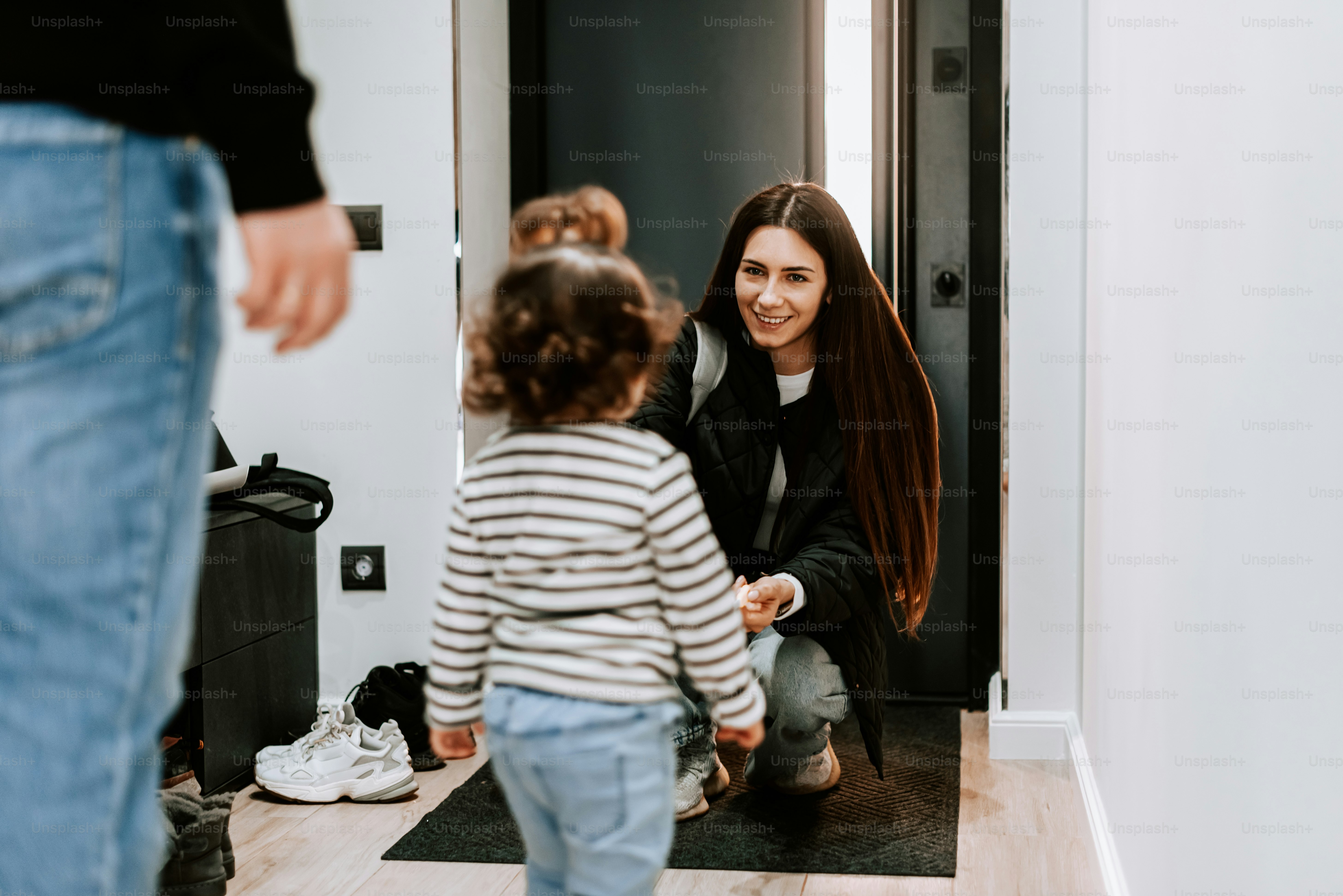a woman holding a child's hand as they stand in front of a door