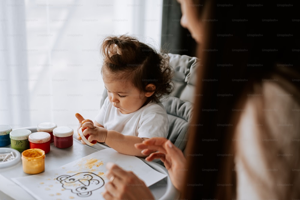 a little girl sitting in a high chair with her mother