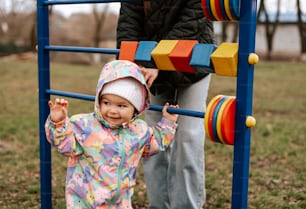 a little girl standing next to a man on a playground