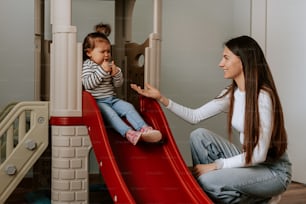 a woman playing with a child on a slide