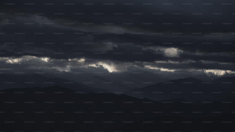 une photo en noir et blanc de nuages sombres au-dessus des montagnes