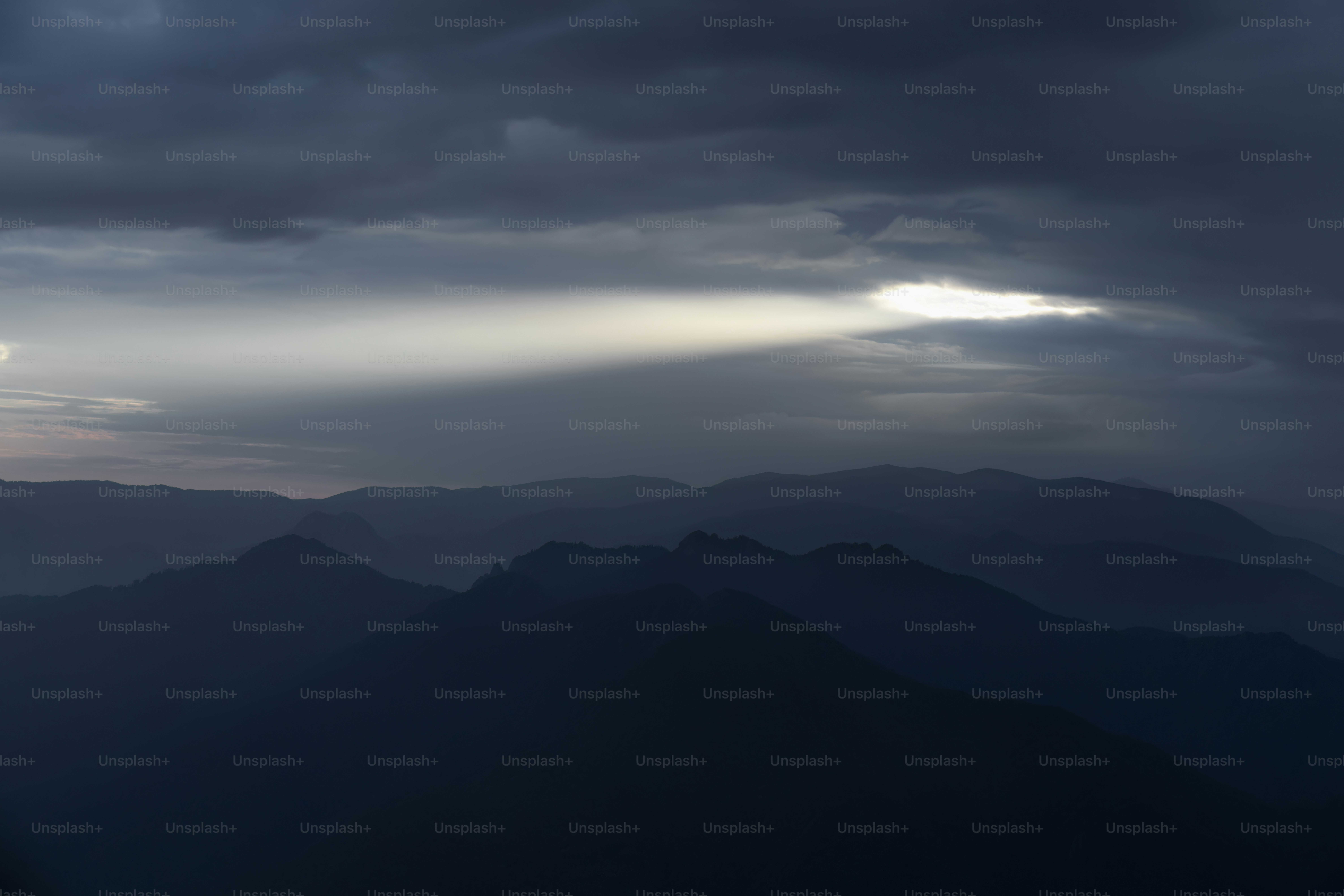 O sol está brilhando através das nuvens sobre as montanhas