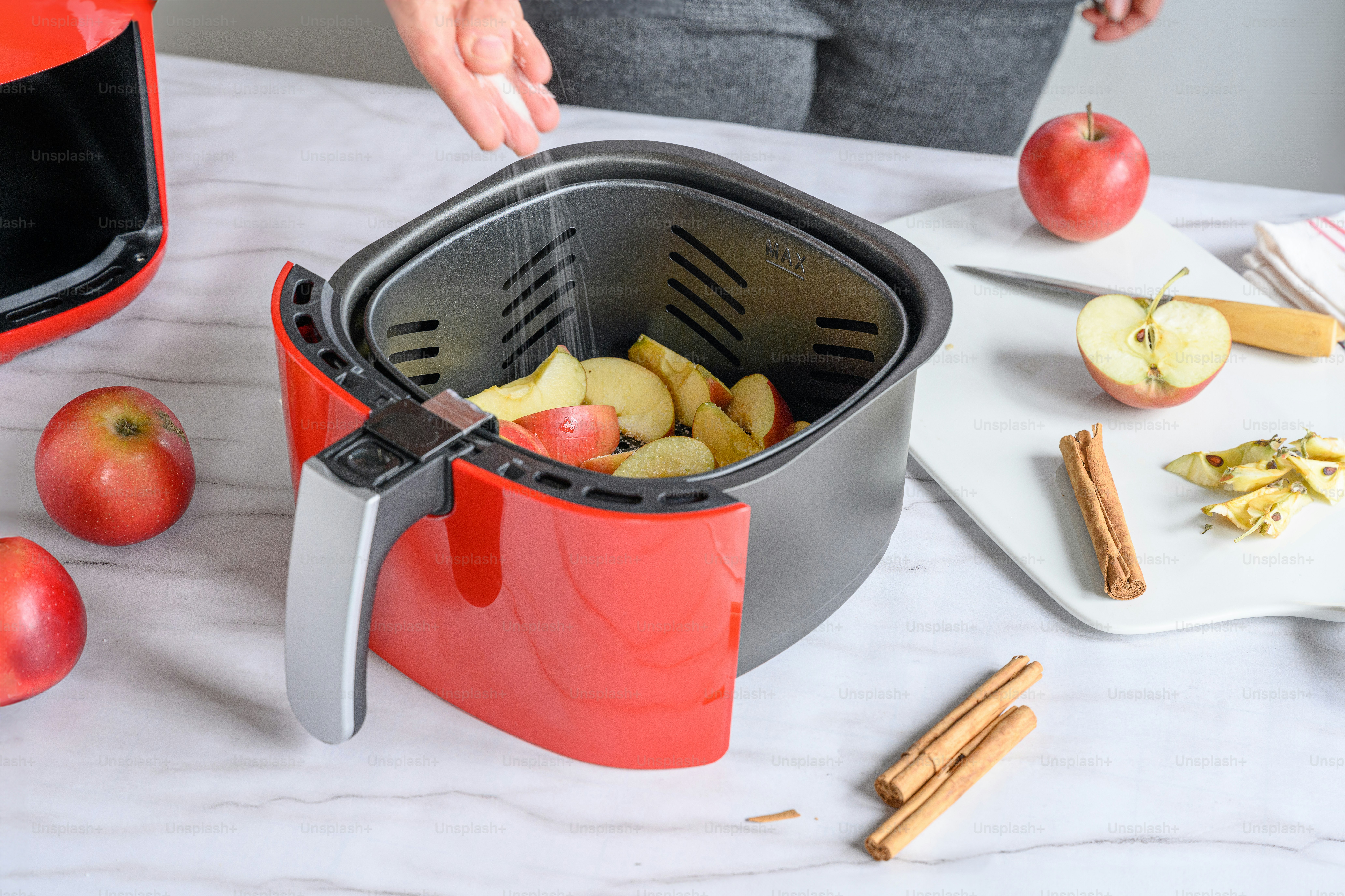 a red juicer filled with apples on top of a table