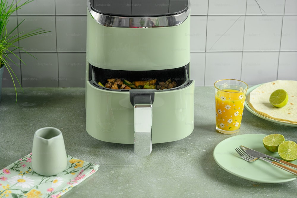a green juicer sitting on top of a counter next to a plate of food