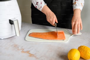 a person cutting a piece of salmon on a cutting board