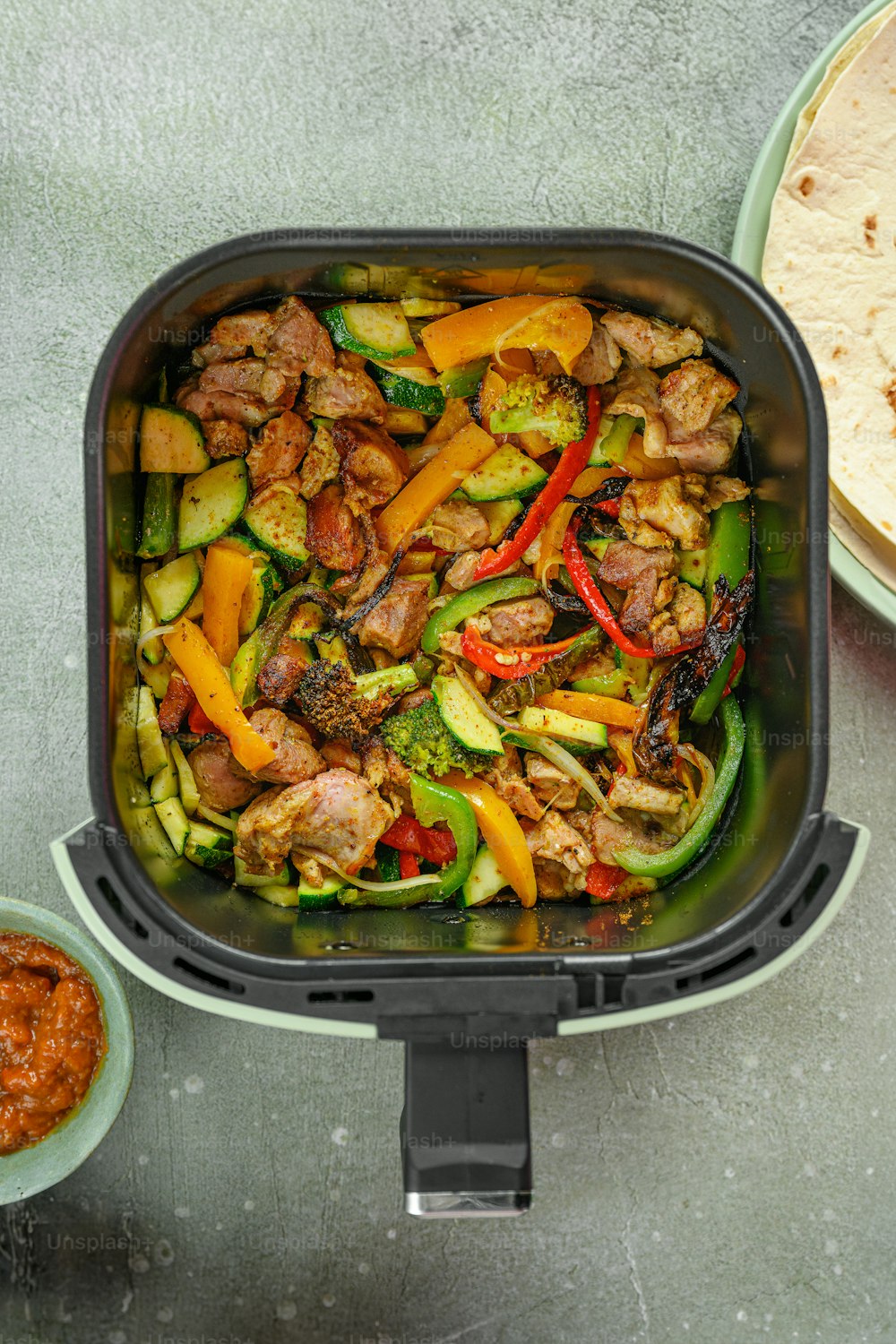 a pan filled with meat and veggies next to a plate of tortill