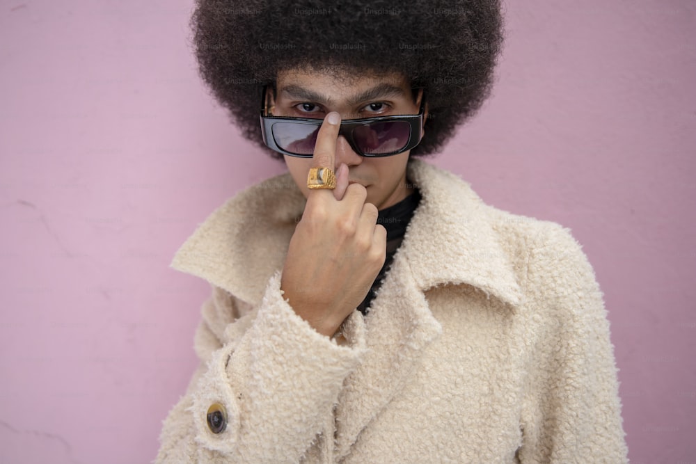 Un homme avec un afro tient son doigt sur son nez