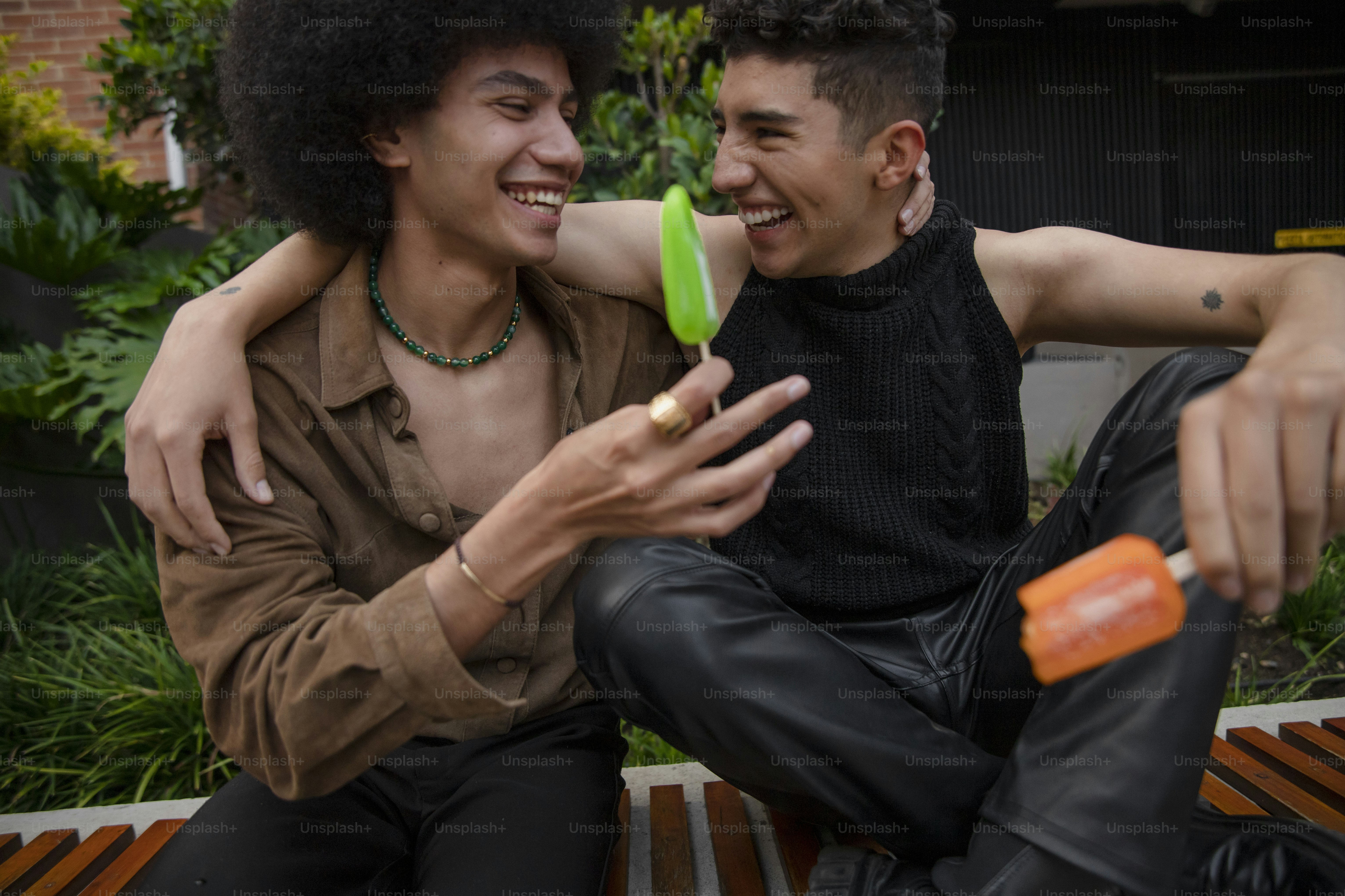 a couple of men sitting on top of a wooden bench