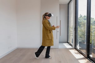 Una mujer con un abrigo amarillo está usando un dispositivo de realidad virtual