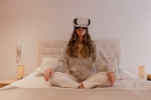 a woman sitting on a bed wearing a virtual headset
