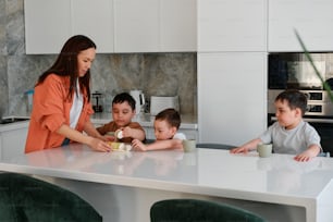 une femme debout au-dessus d’un comptoir de cuisine avec trois enfants