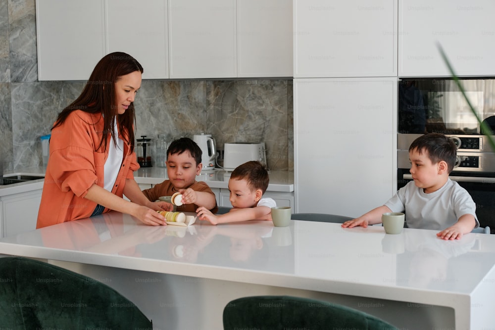 uma mulher em pé sobre um balcão da cozinha com três crianças