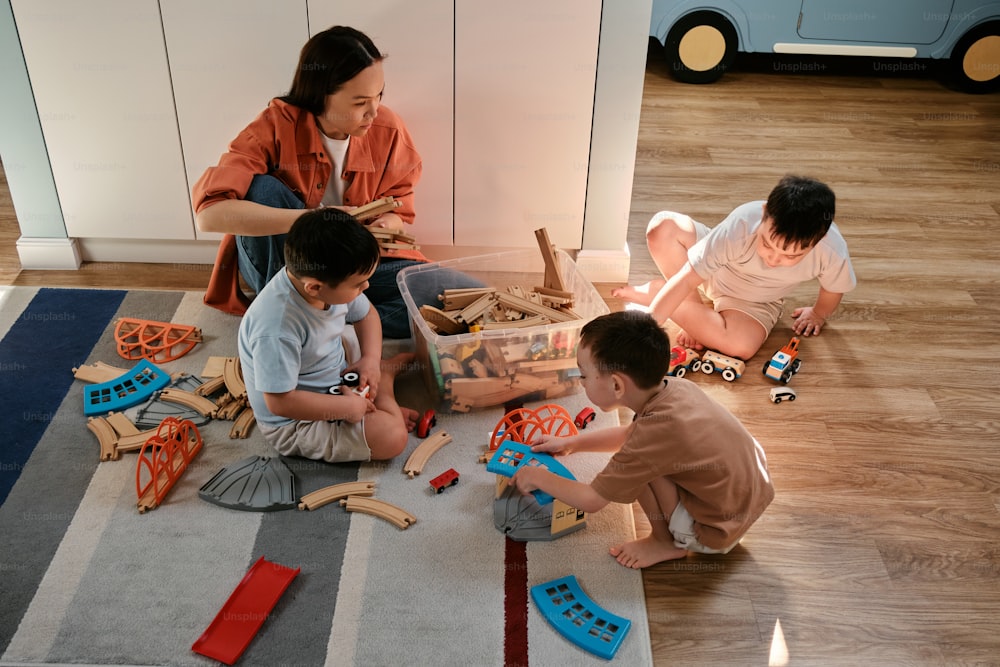 a woman and two boys playing with toys on the floor