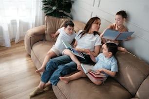 a group of children sitting on a couch reading books