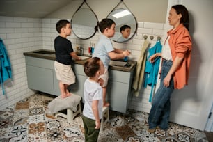a group of children standing around a bathroom sink