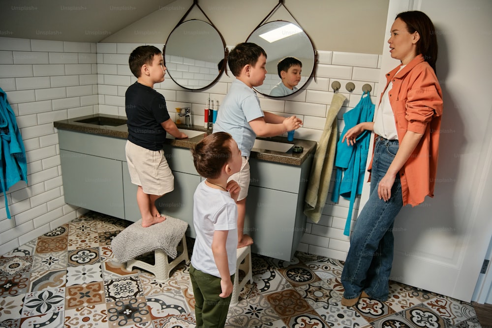 a group of children standing around a bathroom sink