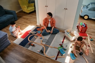 한 여성과 두 아이가 바닥에서 장난감을 가지고 놀고 있다