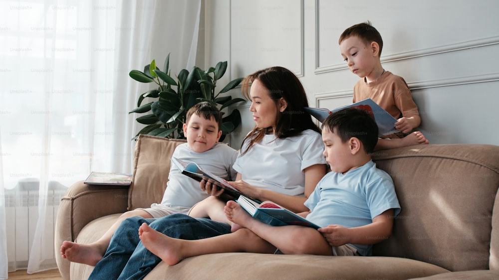 three children sitting on a couch reading books