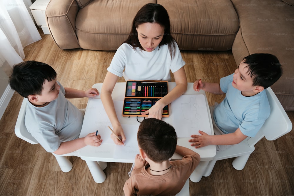 a woman sitting at a table with three children