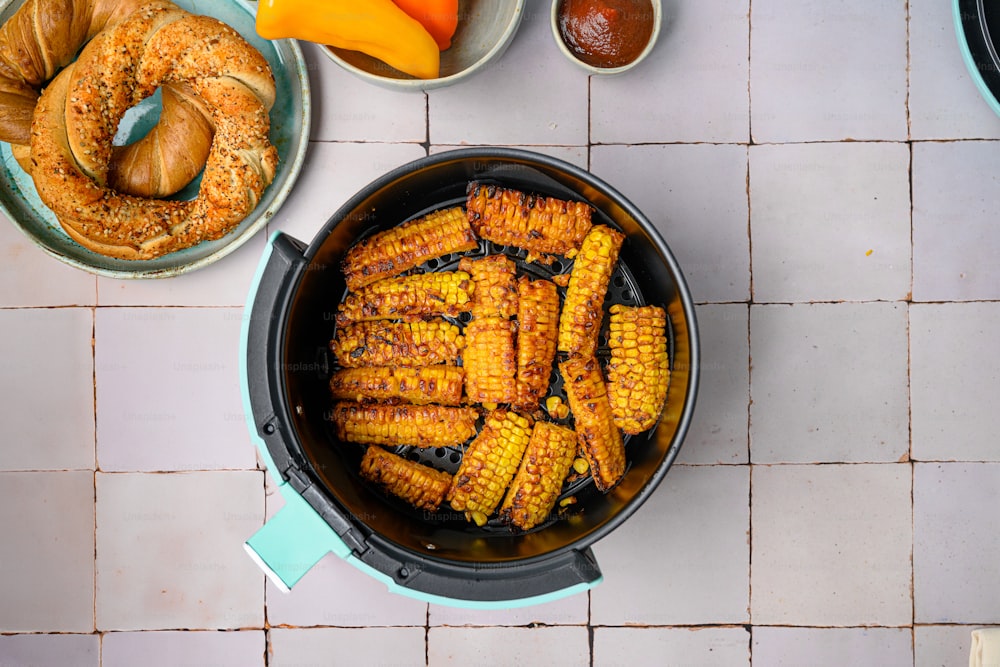 a pan filled with corn on the cob next to a bowl of fruit