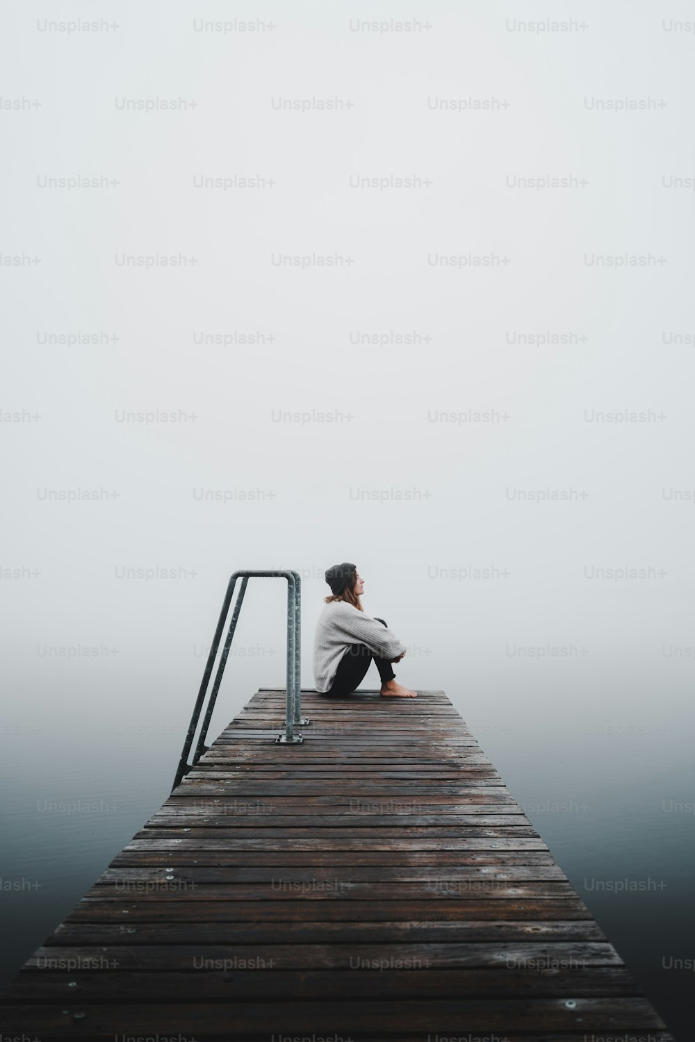 un homme assis sur un quai dans le brouillard