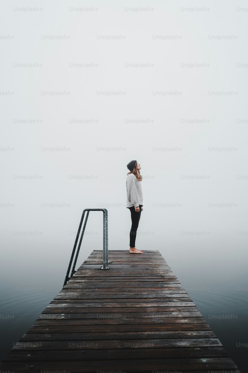 una persona parada en un muelle en la niebla