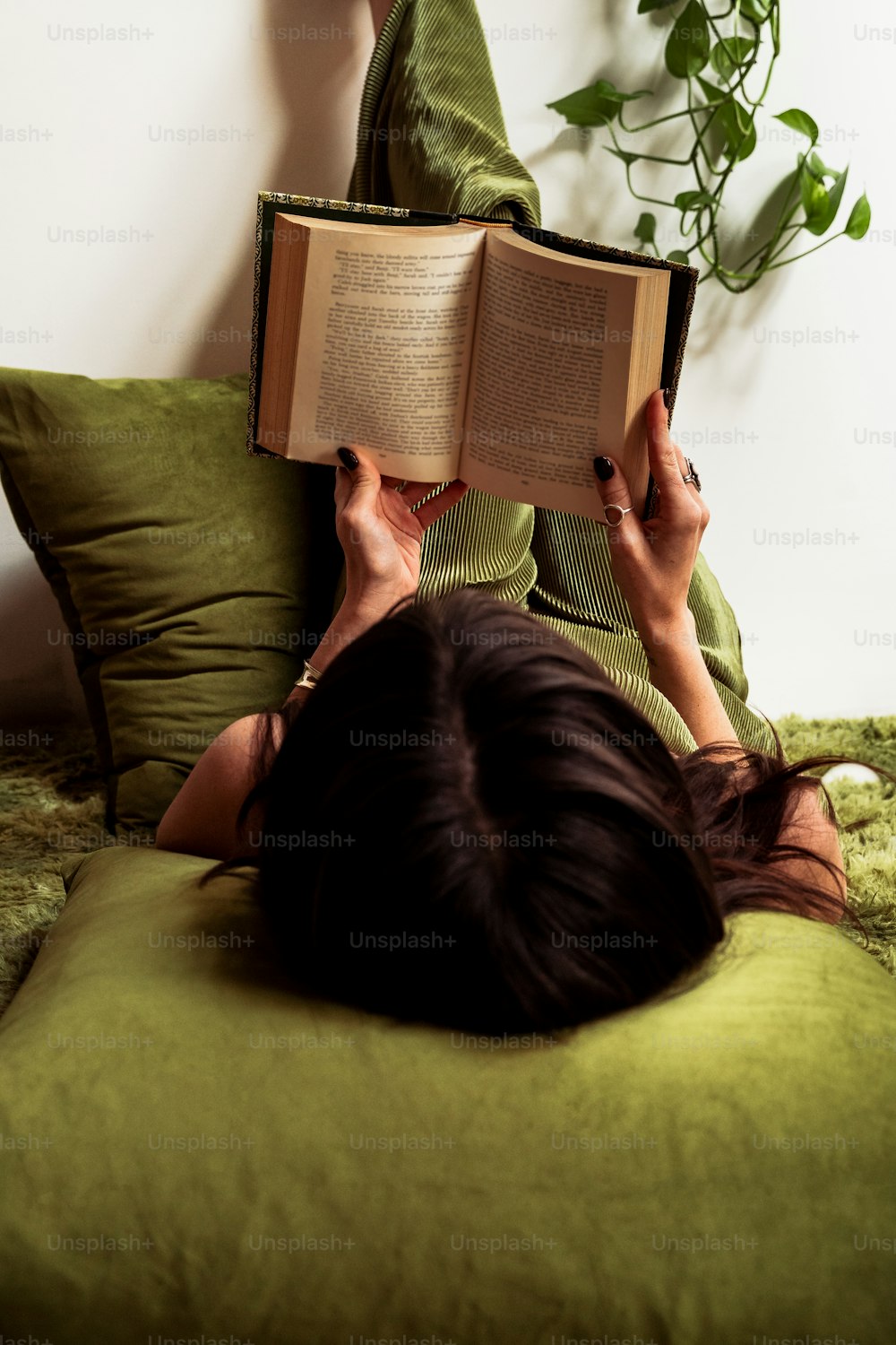 a woman laying on a bed reading a book