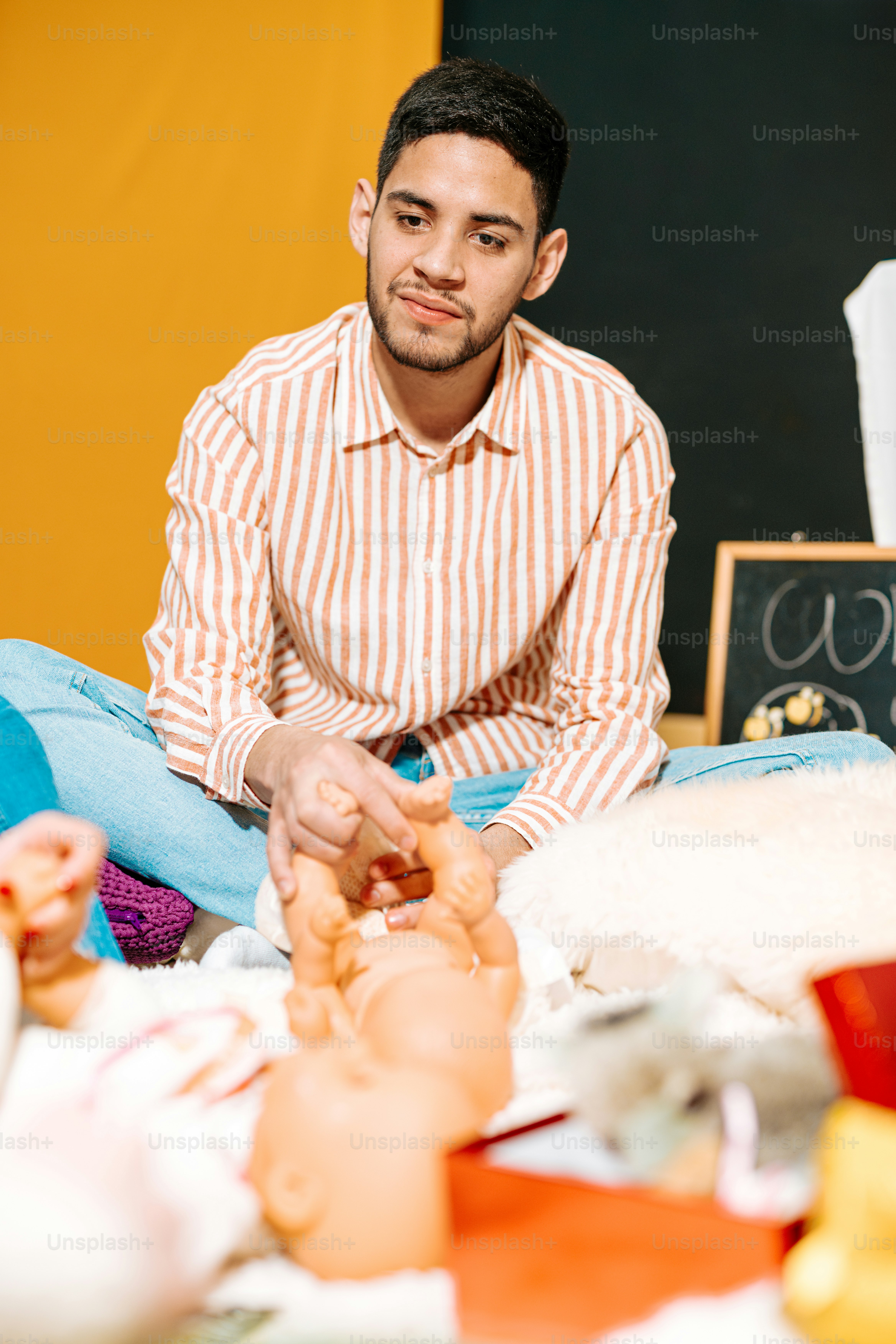 a man sitting on the floor with a doll in front of him