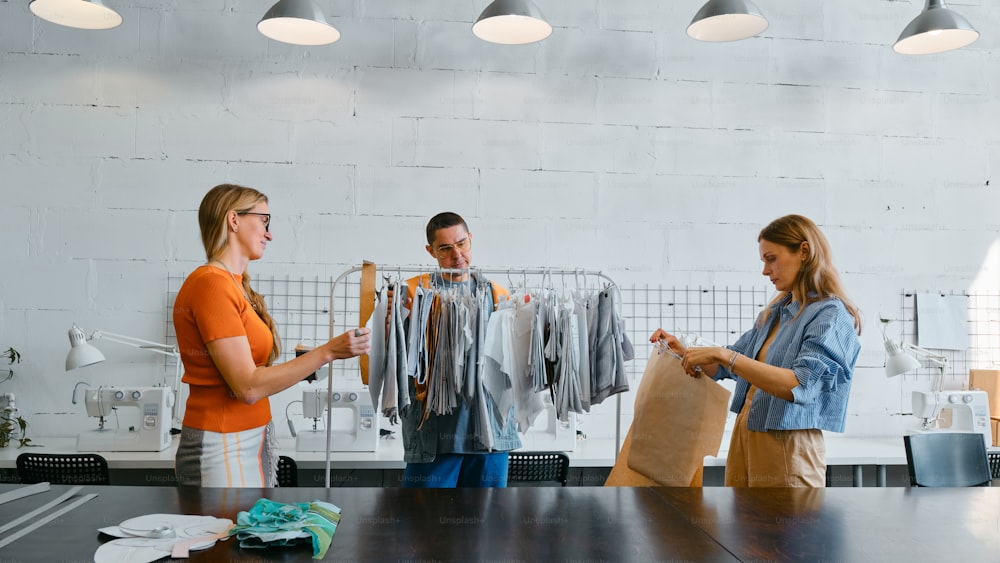 Dos mujeres y un hombre están parados en una tienda de ropa