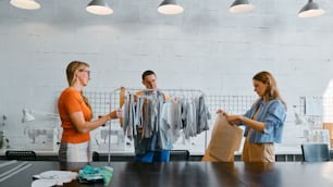 two women and a man are standing in a clothing store