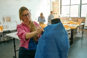 a woman in a pink shirt is working on a piece of clothing