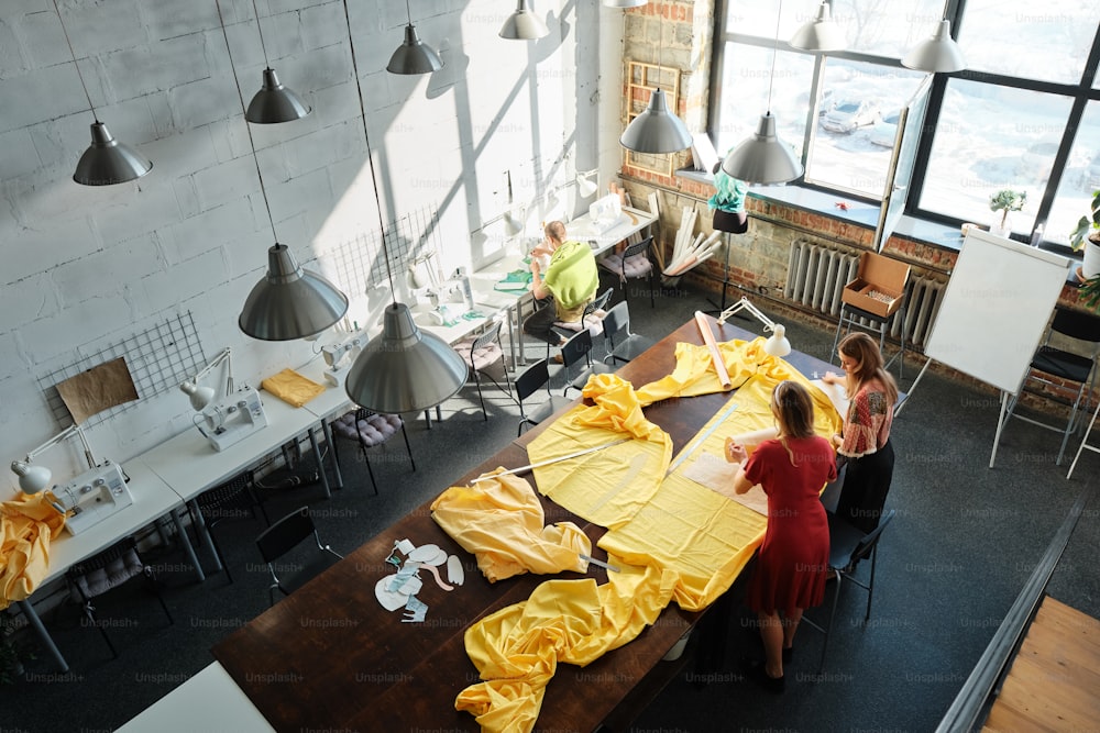 um grupo de pessoas em pé ao redor de uma mesa coberta de pano amarelo