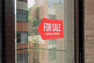 a red for sale sign sitting on the side of a window