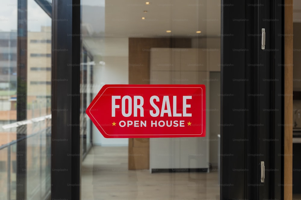 a red for sale sign in front of a glass door