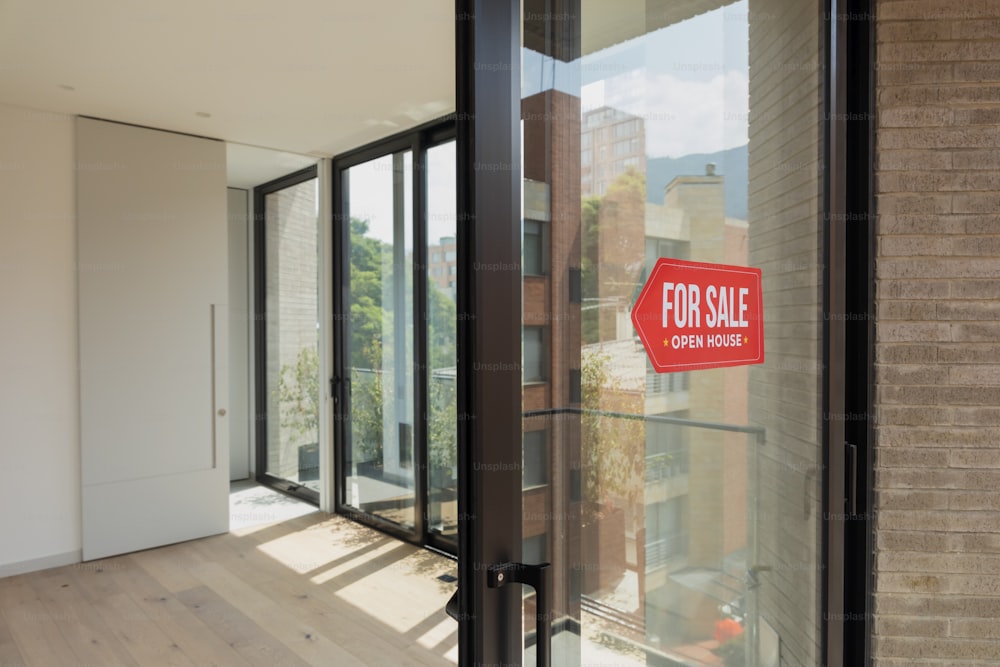 a red for sale sign on a glass door