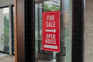 a red for sale sign hanging on a glass door
