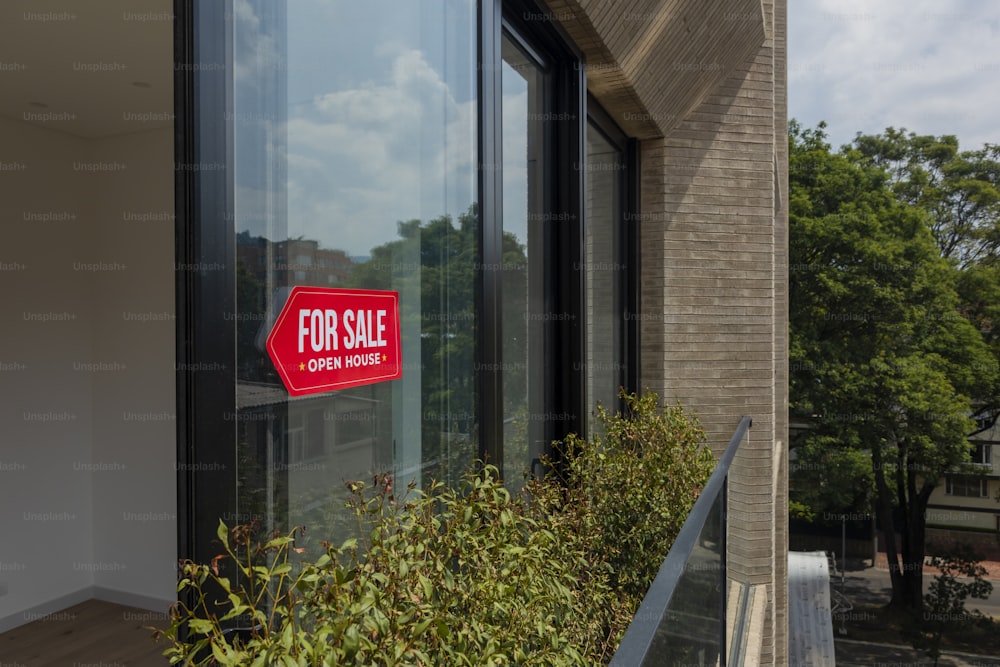 Un letrero rojo de venta sentado en el costado de un edificio