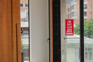 a red for sale sign on a glass door
